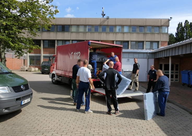 Gefangene laden Hilfsgüter auf einen Transporter