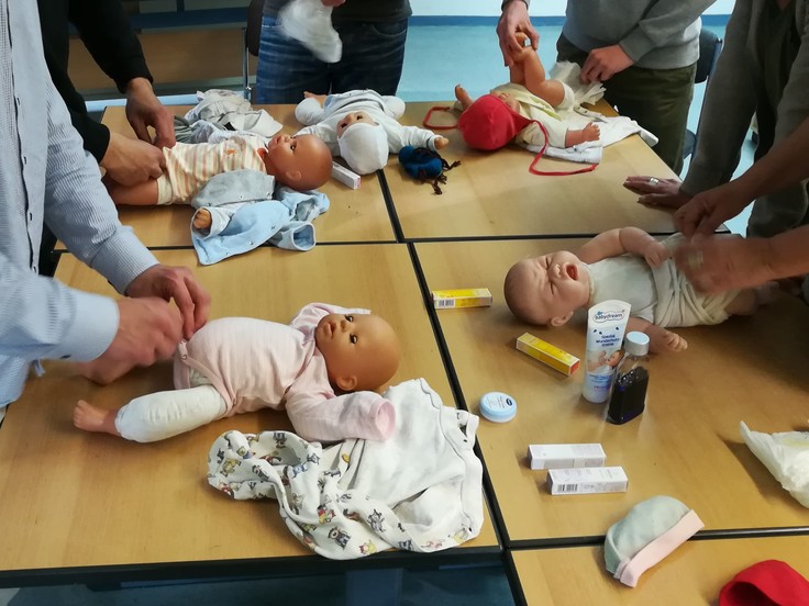 Vier Babypuppen werden von Inhaftierten gewickelt
