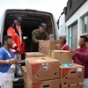 Gefangene laden Hilfsgüter auf einen Transporter für Interhelp
