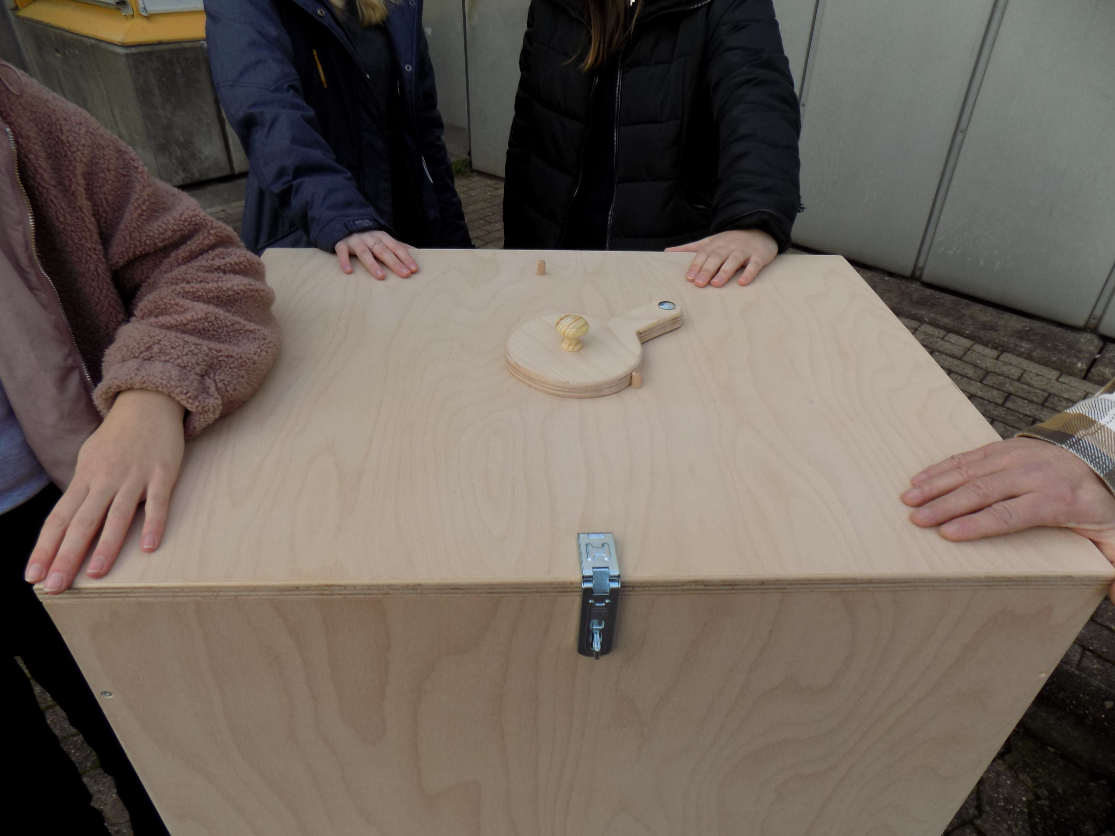 Eine Holzkiste mit Händen von externen Personen, ein Umweltprojekt "Für die Tonne"